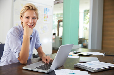 Smiling woman sitting at a desk using a laptop